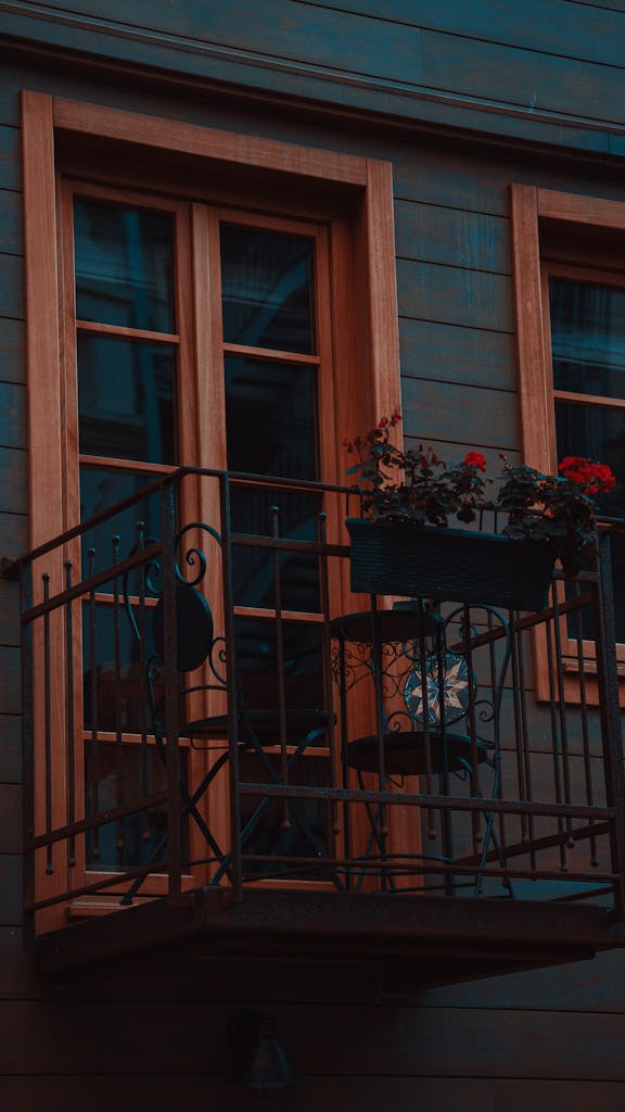 Cozy urban balcony with red flowers and decorative railing, creating a romantic atmosphere.