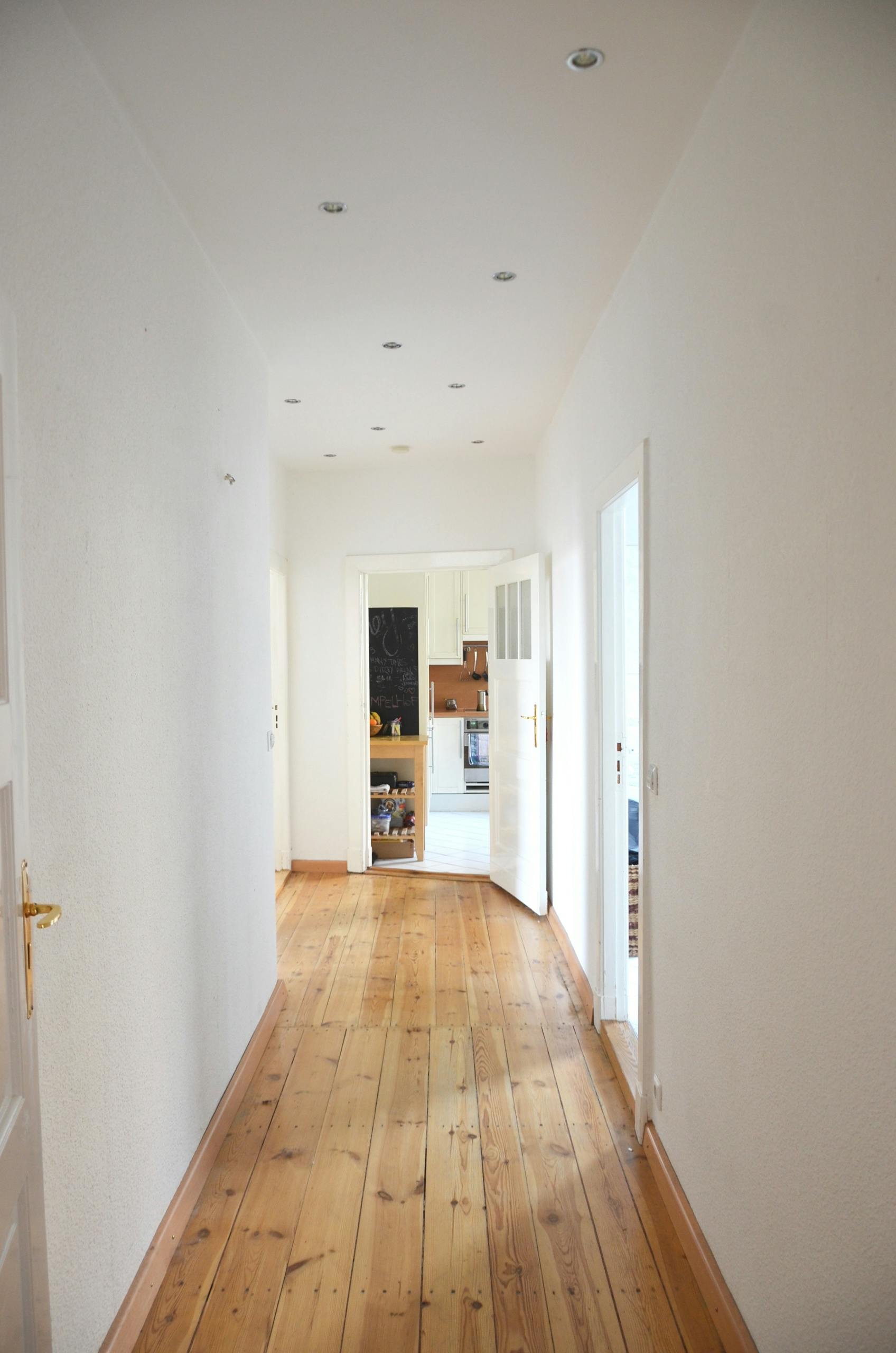 Interior of spacious apartment corridor with white walls and wooden laminate on floor
