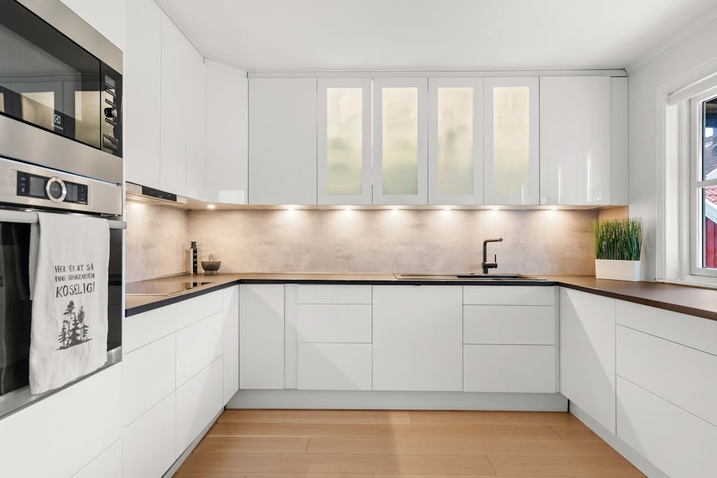 Sleek white kitchen with modern cabinets, wood countertops, and ambient lighting.